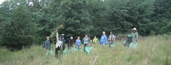 group of volunteers with full trash bags in grassy field