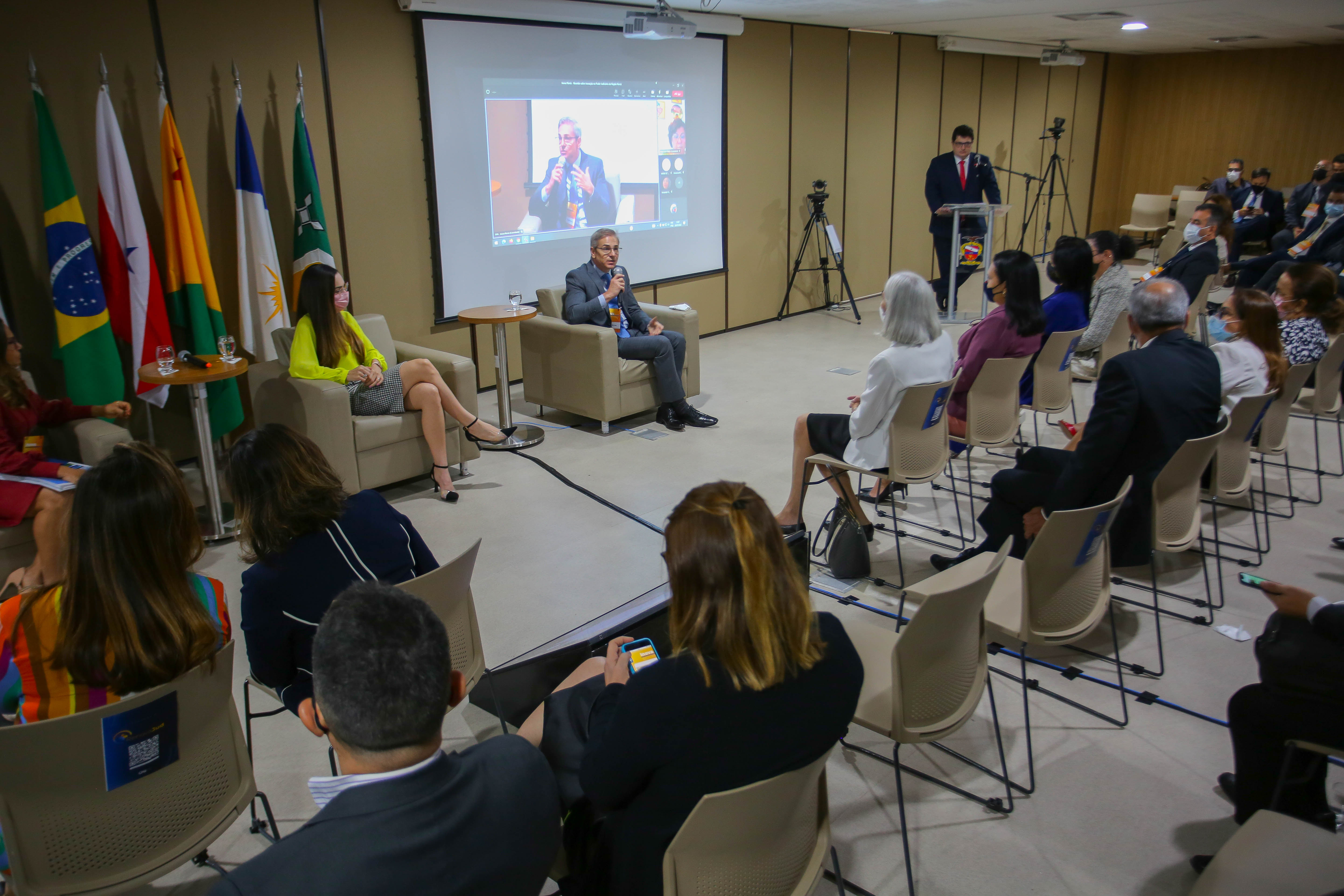 Imagem mostra grupo de pessoas, com o Juiz secretário-geral do Tribunal de Justiça falando ao microfone sobre o projeto do Fórum Digital