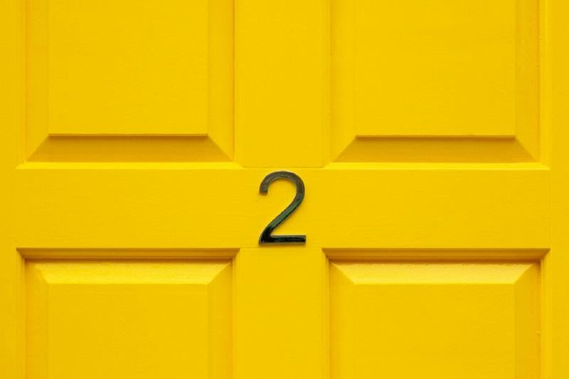 A yellow door with a number on it Description automatically generated