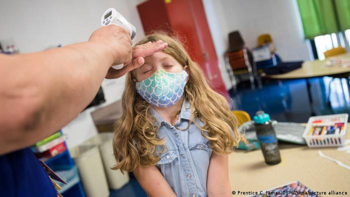 Criança usando máscara de proteção tem a febre medida com termômetro eletrônico em exame de rotina em escola na Califórnia, EUA.