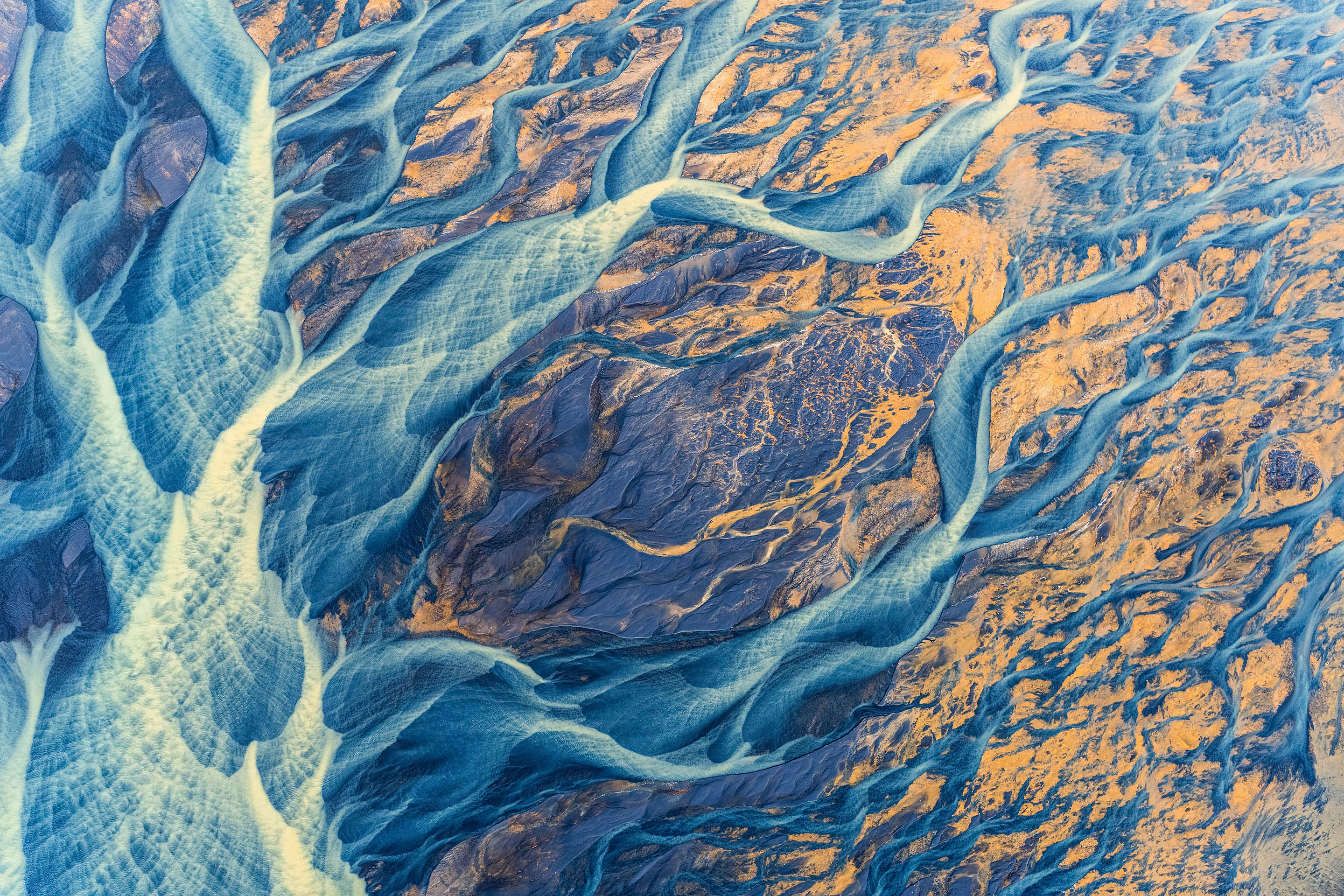 Aerial photo of brightly colored sediment and water flowing across the Icelandic landscape. © undefined