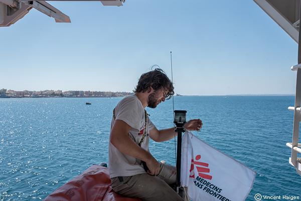 Matthijs, miembro del equipo, coloca una bandera de MSF a la lancha del Geo Barents.