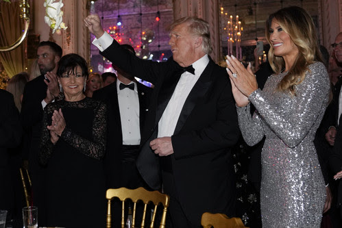 Former President Donald Trump and former first lady Melania Trump arrive in the dining room for a New Years Eve party at Mar-a-Lago, in Palm Beach, Fla., Saturday, Dec. 31, 2022.