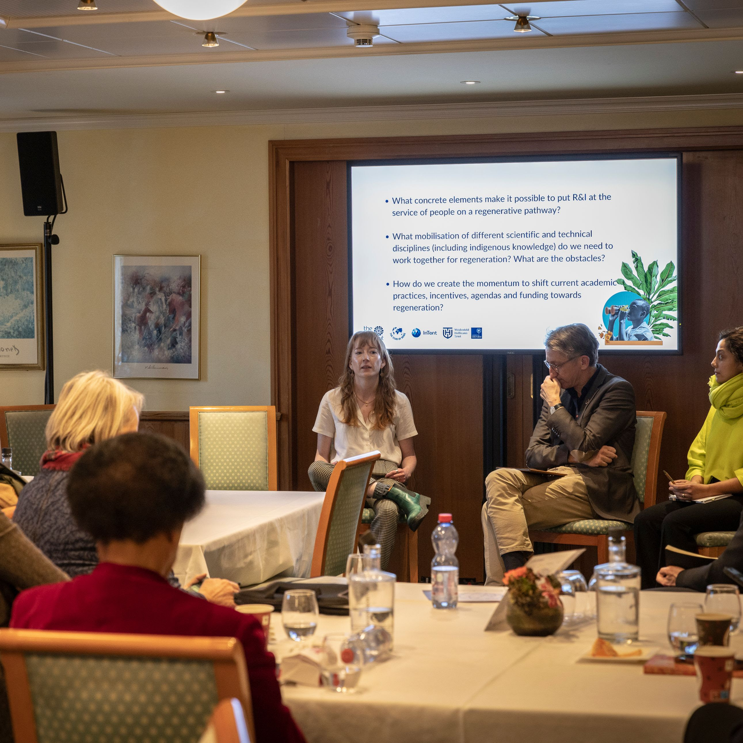 a group of people sitting around a table listening to a presentation