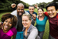 Photograph of diverse group of adults smiling at the camera with a park-like setting in the background.