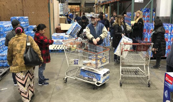 Shoppers wait their turns to pick up toilet paper that had just arrived at a Costco store, Saturday, March 7, 2020, in Tacoma, Wash. Within minutes, several pallets of toilet paper and paper towels were sold out as people continue to stock up on necessities due to fear of the COVID-19 coronavirus. (AP Photo/Ted S. Warren)