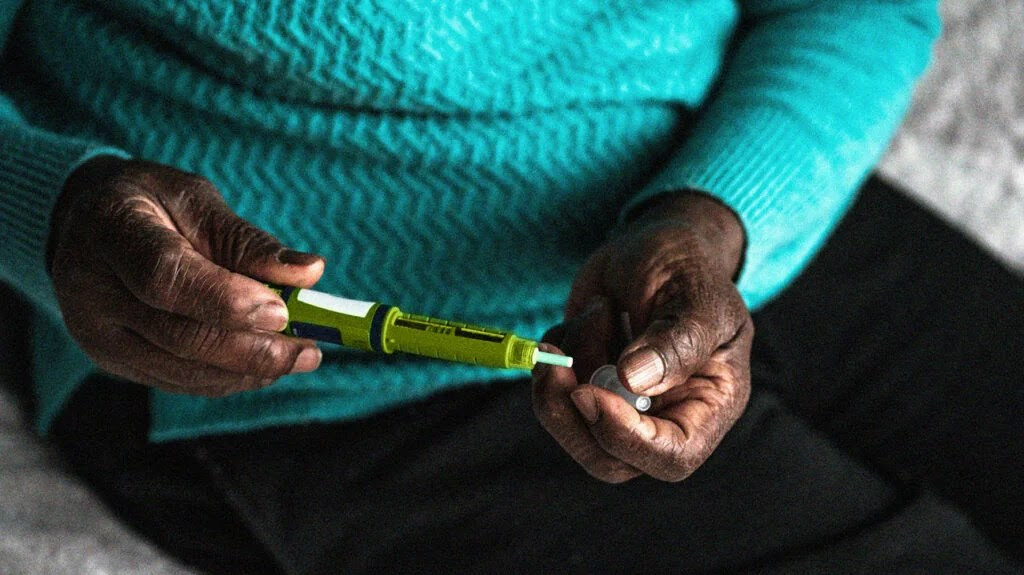 A man carefully holds a syringe