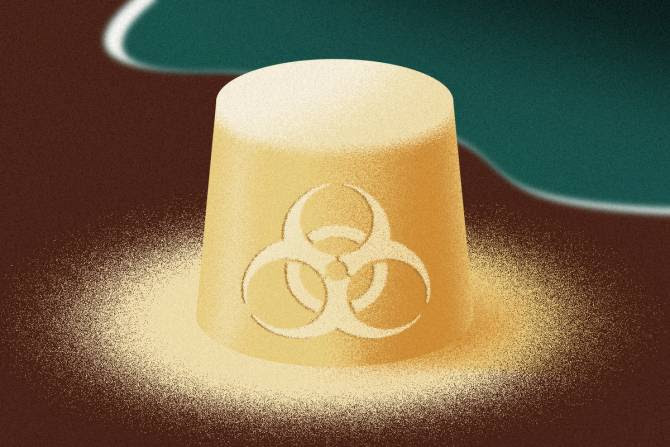 A bucket of sand with a toxic symbol on it at the beach