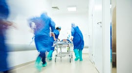 image of hospital providers rushing patient on gurney down hall