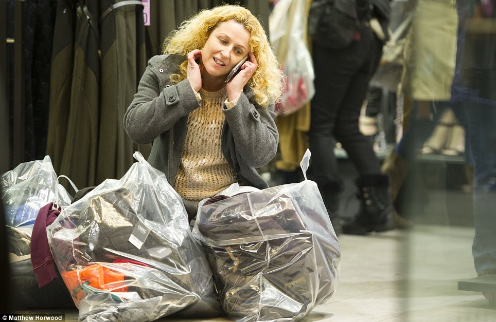 Laden: A woman at the Next branch in Cardiff surrounding by her Boxing Day bargains