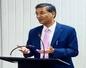 A person in a suit speaking at a podiumDescription automatically generated with medium confidence