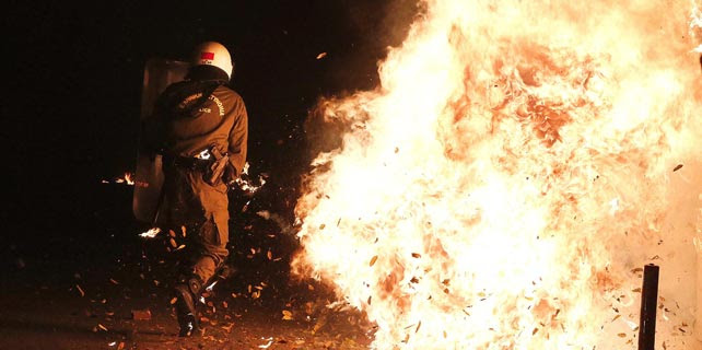 Un antidisturbios esquiva un cóctel molotov durante los enfrentamientos de la noche del sábado en Atenas. REUTERS/Alkis Konstantinidis