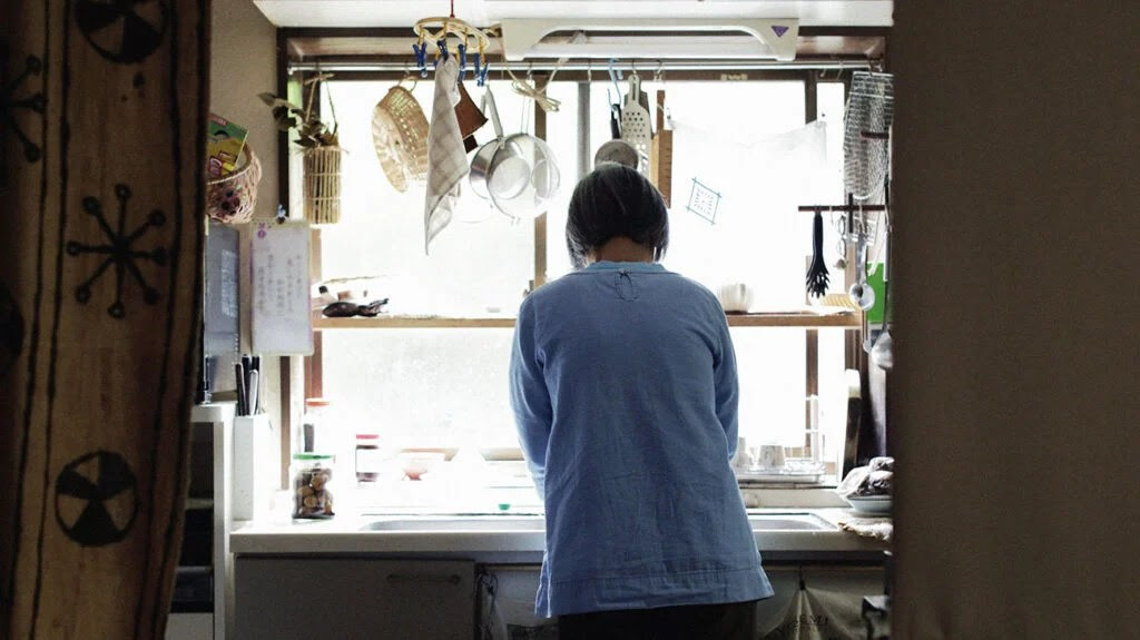 A person at the kitchen sink with their back to camera-1.