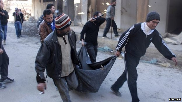 Men carry the body of an executed detainee found at a children's hospital occupied by the Islamic State in Iraq and the Levant (ISIS) in Aleppo (8 January 2014)