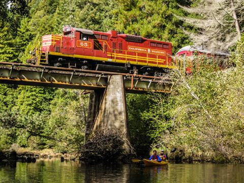 The Mendocino County Skunk Train crosses a bridge while passing over a river