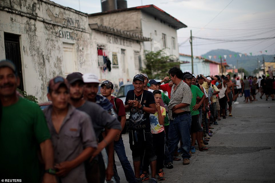 Migrants, part of  the first caravan of 7,000 from Central America en route to the United States, wait in line for food donations in San Pedro Tapanatepec, Mexico, Sunday