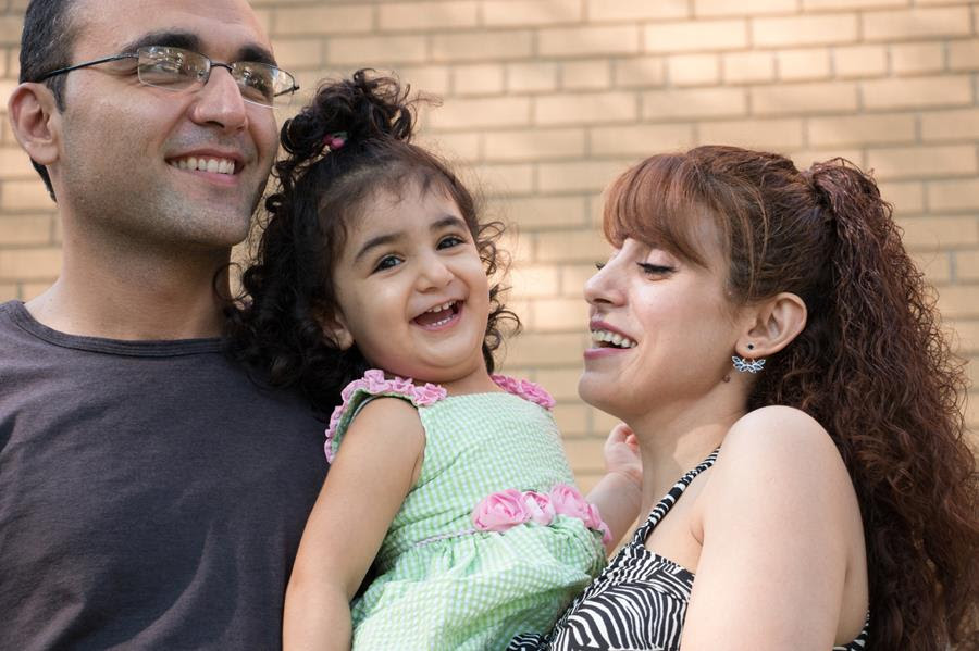 A father and mother hold their young daughter.