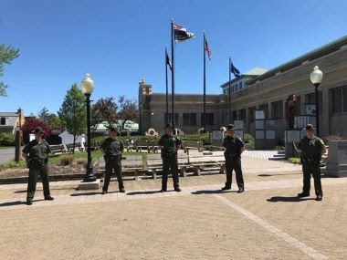 five eco officers standings in front af a building with flags flying behind them