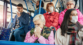 people riding mass transit with either a respiratory mask on or who are sneezing into a tissue