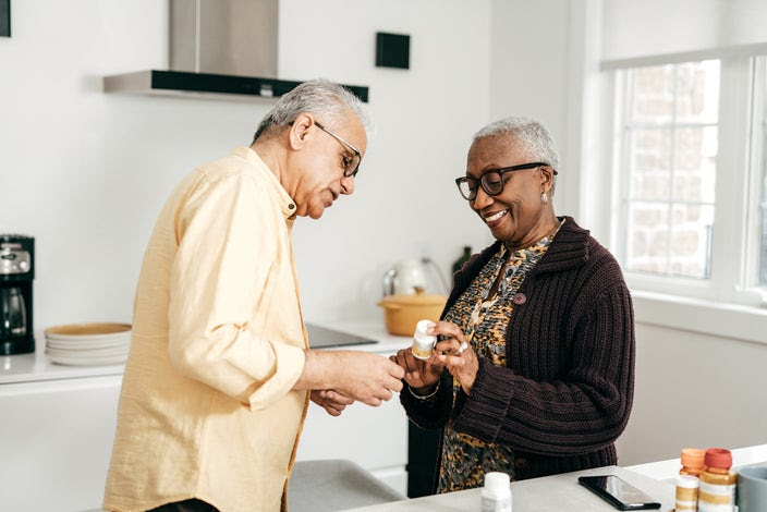 Elderly couple reviewing their prescriptions together in the kitchen.