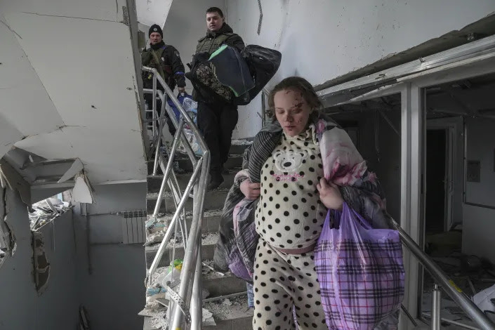 An injured pregnant woman walks downstairs in the shell-damaged maternity hospital in Mariupol. 