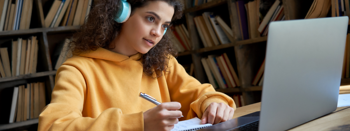 Student with headphones on works in front of laptop