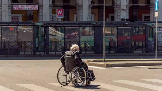 Un anciano cruza la calle en silla de ruedas.