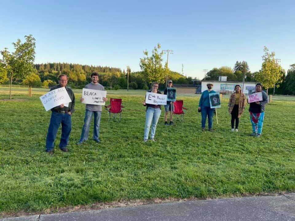 People at a roadside rally holding Black Lives Matter signs
