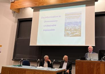 Bruce Everett ’69 shows a slide reading, “Decarbonization is: unnecessary, undesirable, impossible.”