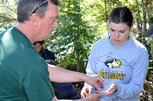 Historian Barry James hands a piece of pottery to a student on an archaeological dig in the Upper Peninsula.