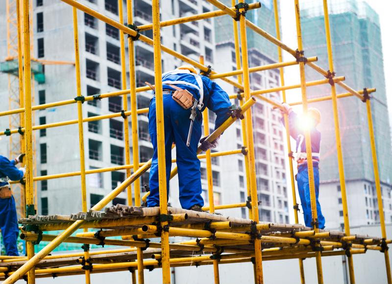 Workers weld on scaffolding.