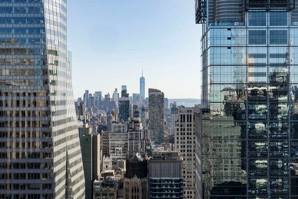 An aerial view of the New York skyline, sandwiched between two gleaming skyscrapers.