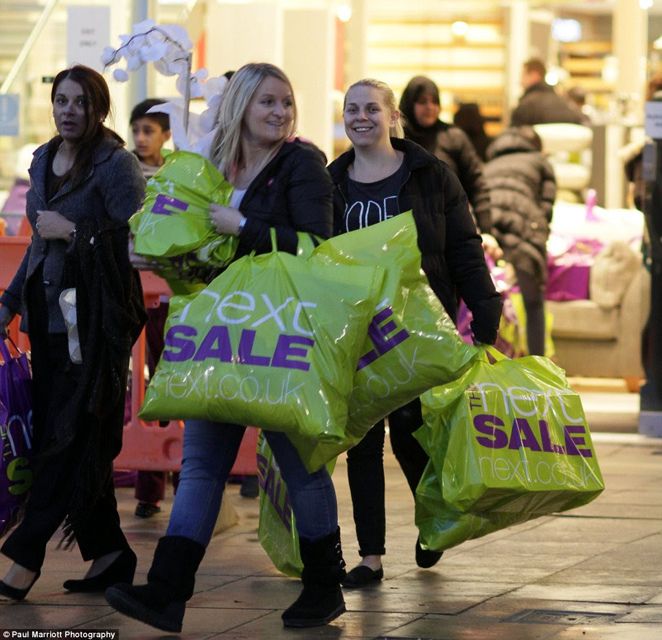 Overloaded: Shoppers struggle with large bags as they leave the sales at Next in Peterborough this morning