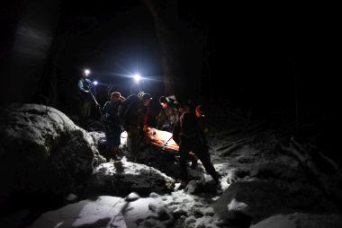 Rangers wearing headlamps check on injured hiker during night rescue