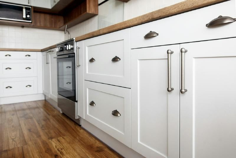 A kitchen with white cabinets and stainless steel appliances Description automatically generated