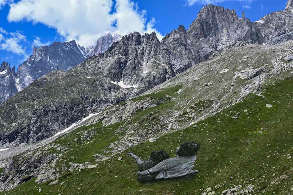 a photo of mountains with a large piece of land art showing a elderly woman and child.