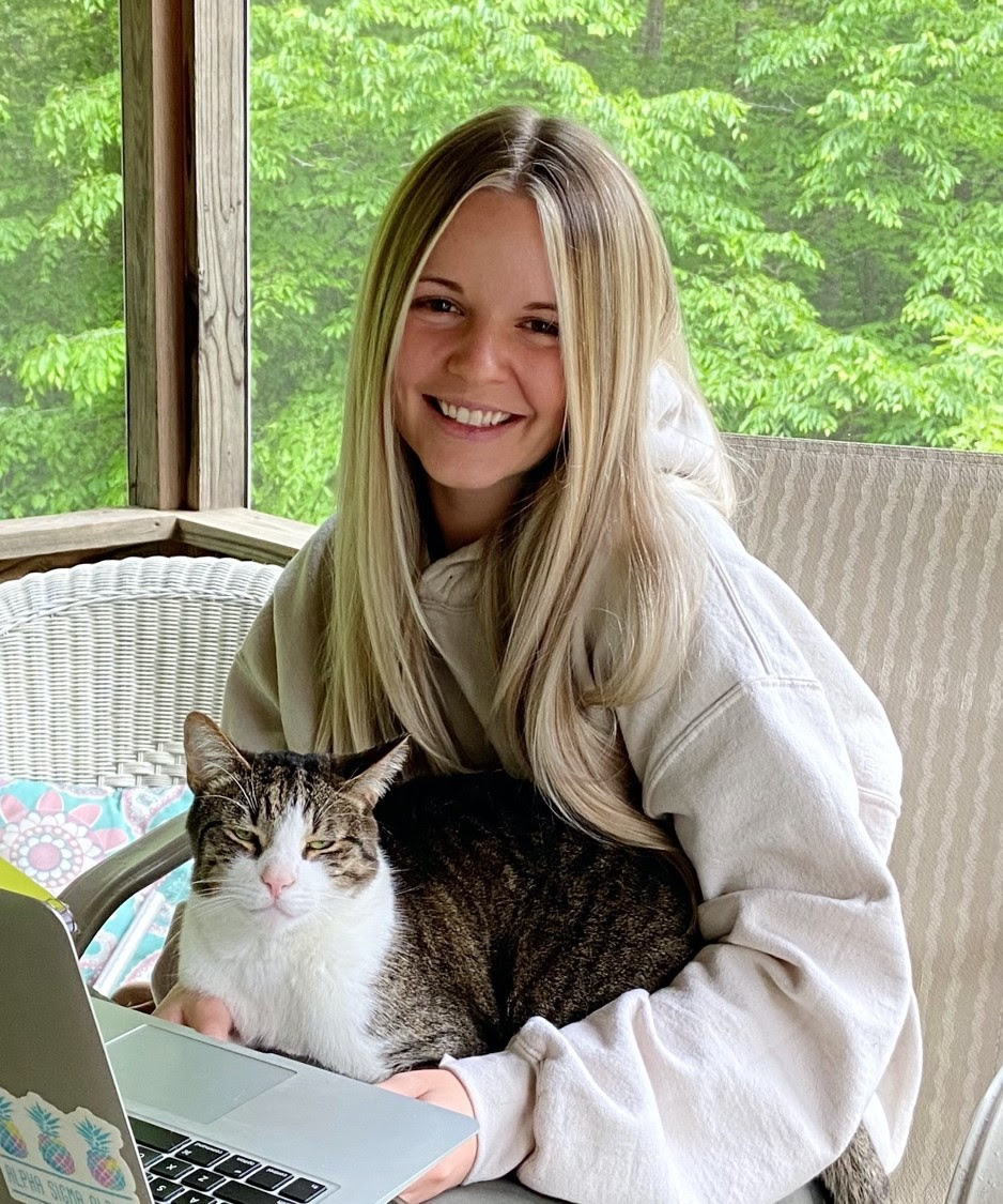 Portrait of female students Shannon Smith posing on a outdoor patio holding her cat Milo. 