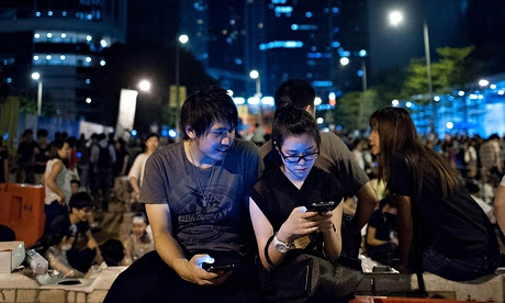 Jóvenes participantes en las protestas en Hong Kong utilizan sus teléfonos inteligentes para comunicarse