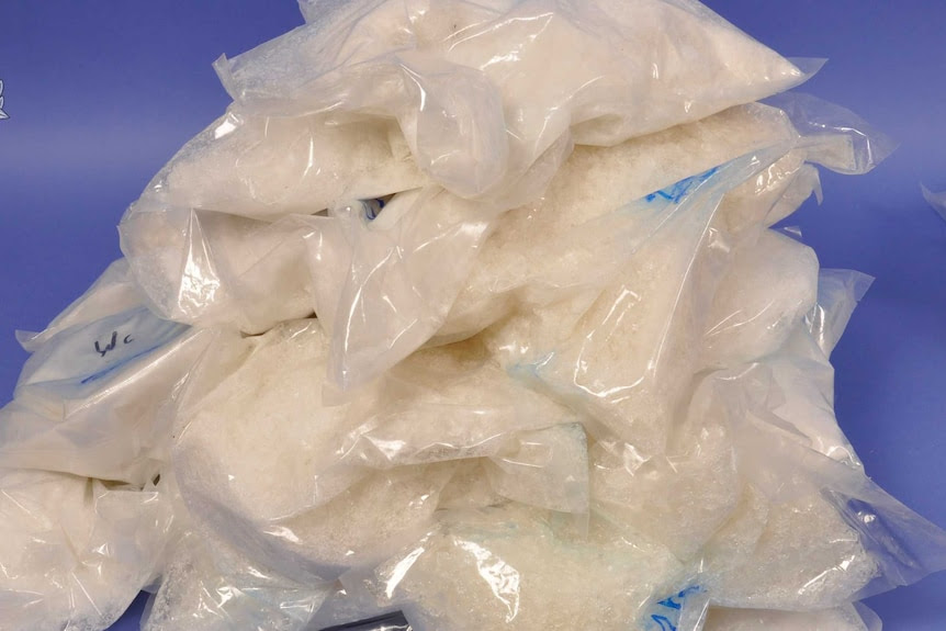 A close-up shot of a pile of clear plastic bags packed with white-coloured illegal drugs.