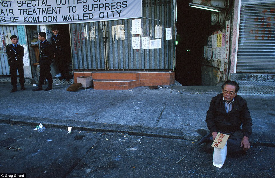 A resident upset with compensation protests on the pavement in front of Walled City during clearance operation by police