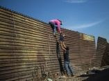 Una familia de migrantes trepa la valla fronteriza entre México y Estados Unidos, cerca del cruce fronterizo de El Chaparral, en Tijuana. Foto: Pedro Pardo/ AFP. caravana-migrante-en-frontera-pedro-pardo-afp