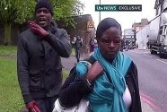 Michael Adebolajo, holding a knife in his bloody-covered hand, rants in front of a camera near where he murdered Lee Rigby, whose body can be seen lying in the road.