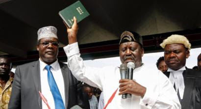 Raila Odinga raises a bible as he "takes an oath" during an unofficial "swearing-in" ceremony in Nairobi on 30 January 2018.