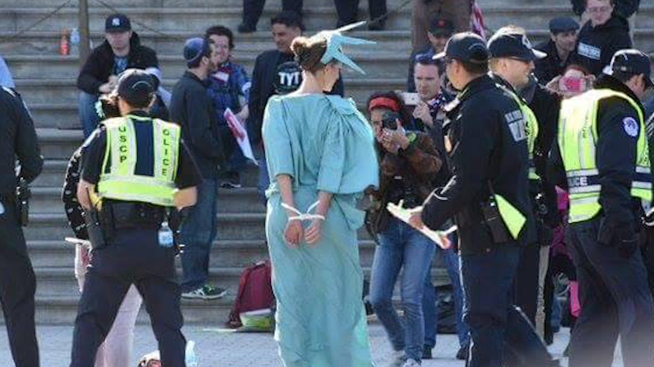 Person in Statue of Liberty costume cuffed by police
