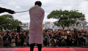 Indonesia: Gay couple flogged over 80 times, woman caned for selling alcohol, crowd screams “Hit them harder”