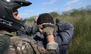 A US border patrol agent leads undocumented immigrants through the brush after capturing them near the Mexico border on 7 December 2015 near Rio Grande City, Texas.