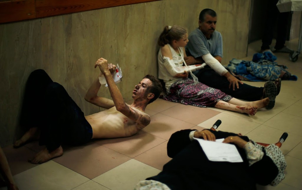 Palestinians, who medics said were wounded during heavy Israeli shelling, sit at a hospital in Gaza City July 20, 2014.  REUTERS/Mohammed Salem