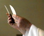 Christian priest's hand holding thin, white Communion wafers