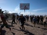 Decenas de migrantes huyen de los gases lacrimógenos. Foto: Guillermo Arias/ AFP. caravana-migrante-en-frontera-guillermo-arias-afp