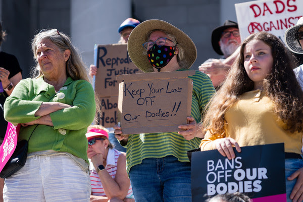A woman attending a rally holds a sign reading, “Keep Your Laws OFF Our Bodies"